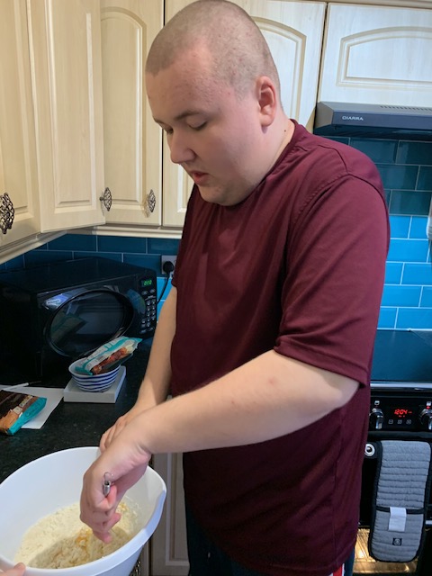 SEN Adult (Autism and Learning Difficulties) baking, holding a stirring spoon and bowl. Having fun. Improving hand motor skills.